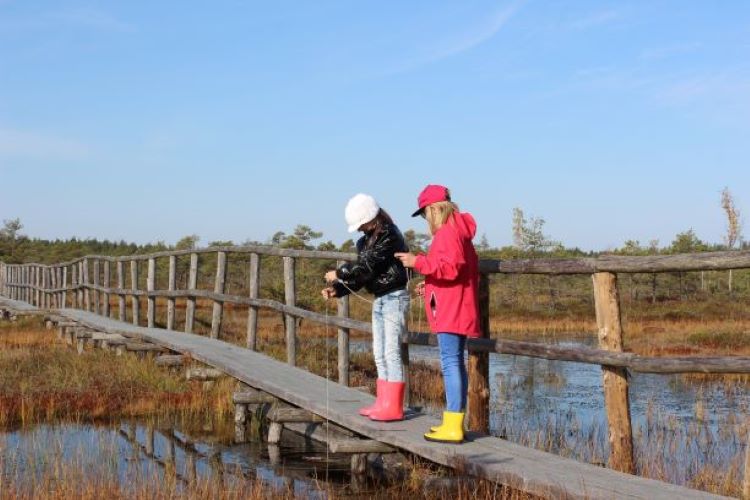 lapsed mõõdavad rabas laudteel seistes lauka sügavust