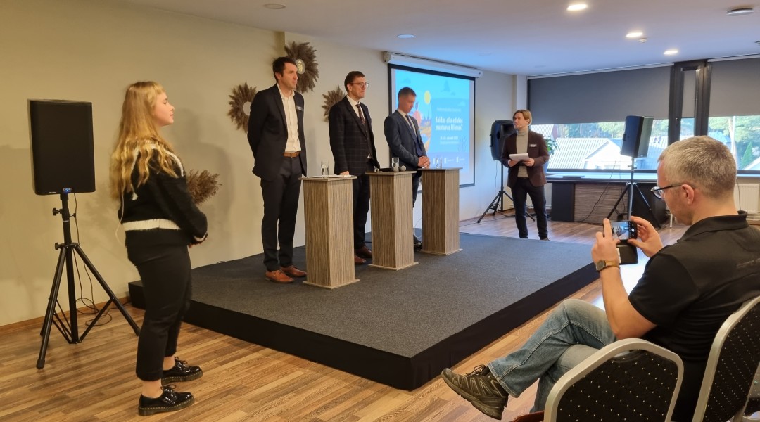 Kolm ülikondades meest seisavad reas ja vastavad noore kliimateadliku blondi tütarlapse küsimustele