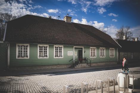 Roheline puidust maja valgete väikeste ruutudega aknaraamidega ja kivist katusega munakivitee ääres