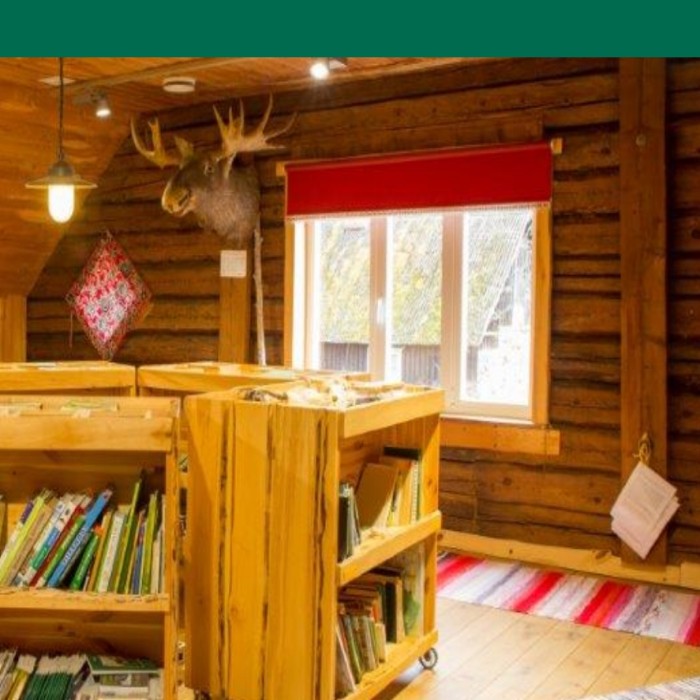 Puidust seinte ja sisustusega hoones on soe valgus, akna kõrval suur põdra pea topis